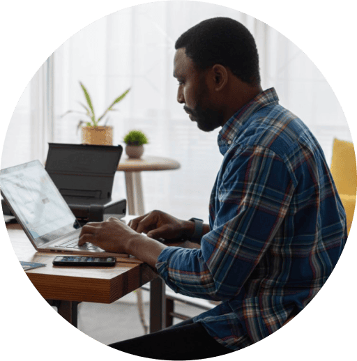 A home worker sat at a desk typing on a laptop.